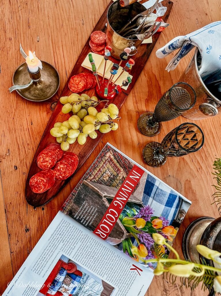 Charcuterie board on antique trapper's board with lit candle and snacks.