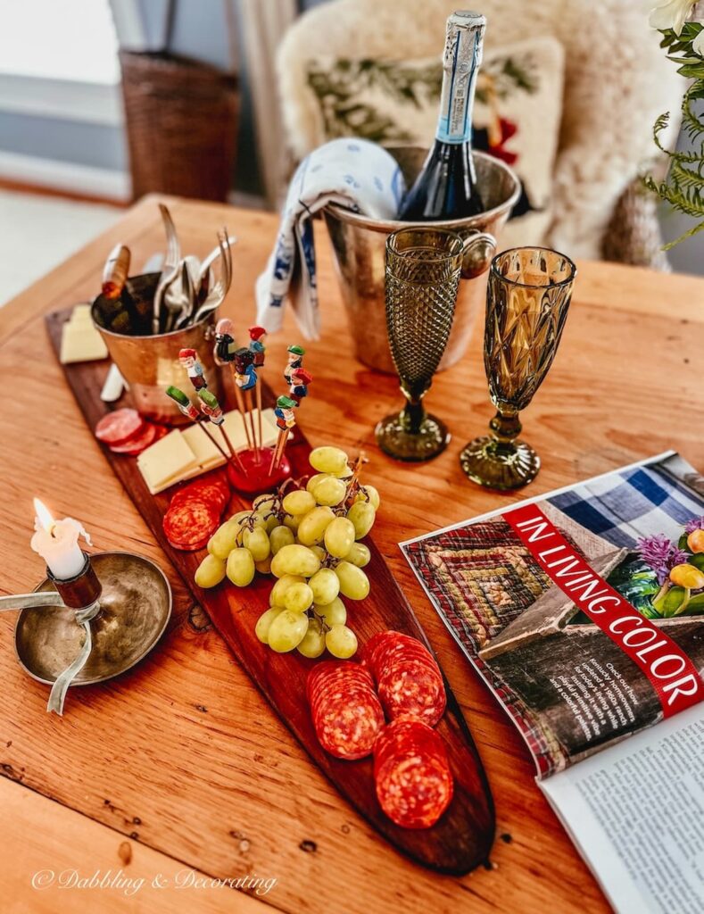 Charcuterie board on antique trapper's board with lit candle and snacks.