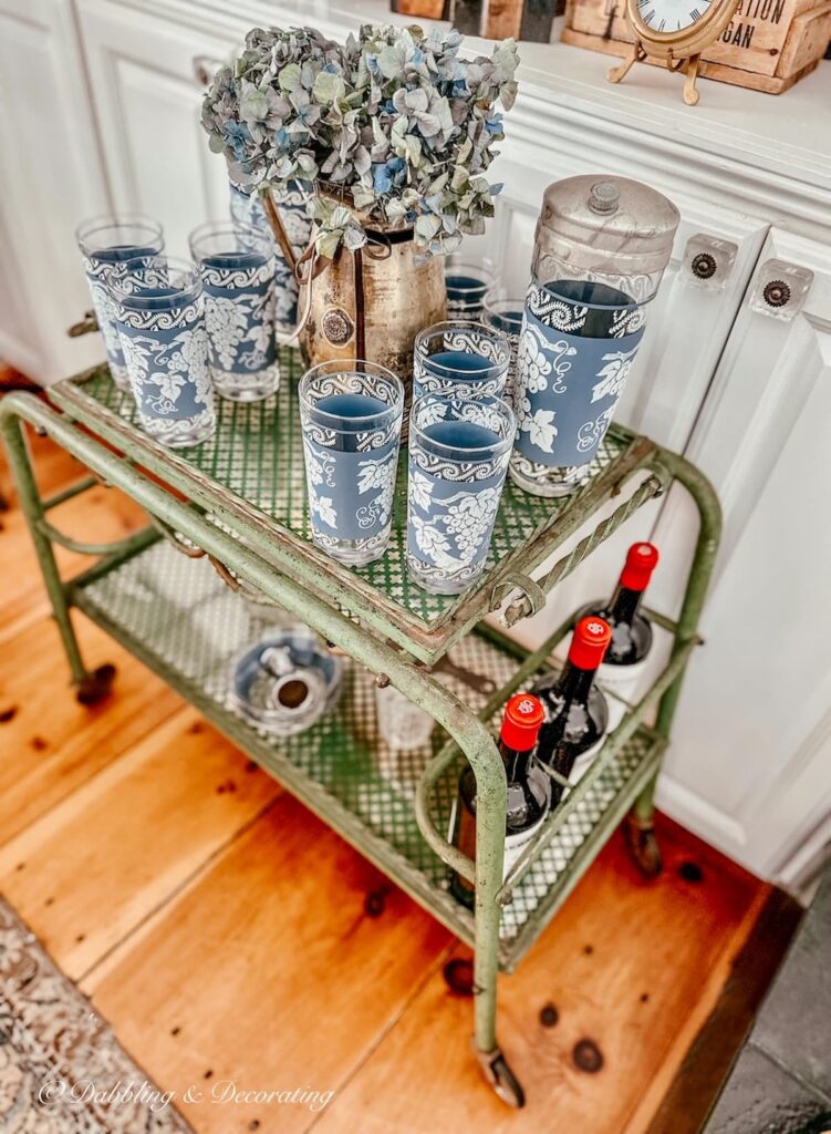 Vintage Jeanette blue barware on antique bar cart as side table in living room.