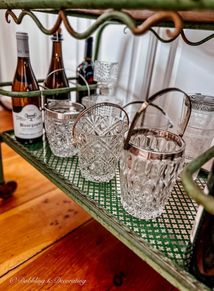 Small crystal ice buckets on antique bar cart.