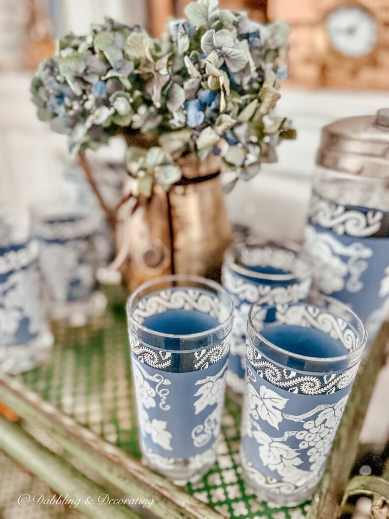 Vintage blue Jeanette Bar Set on antique bar cart. And silver vase with blue hydrangeas.