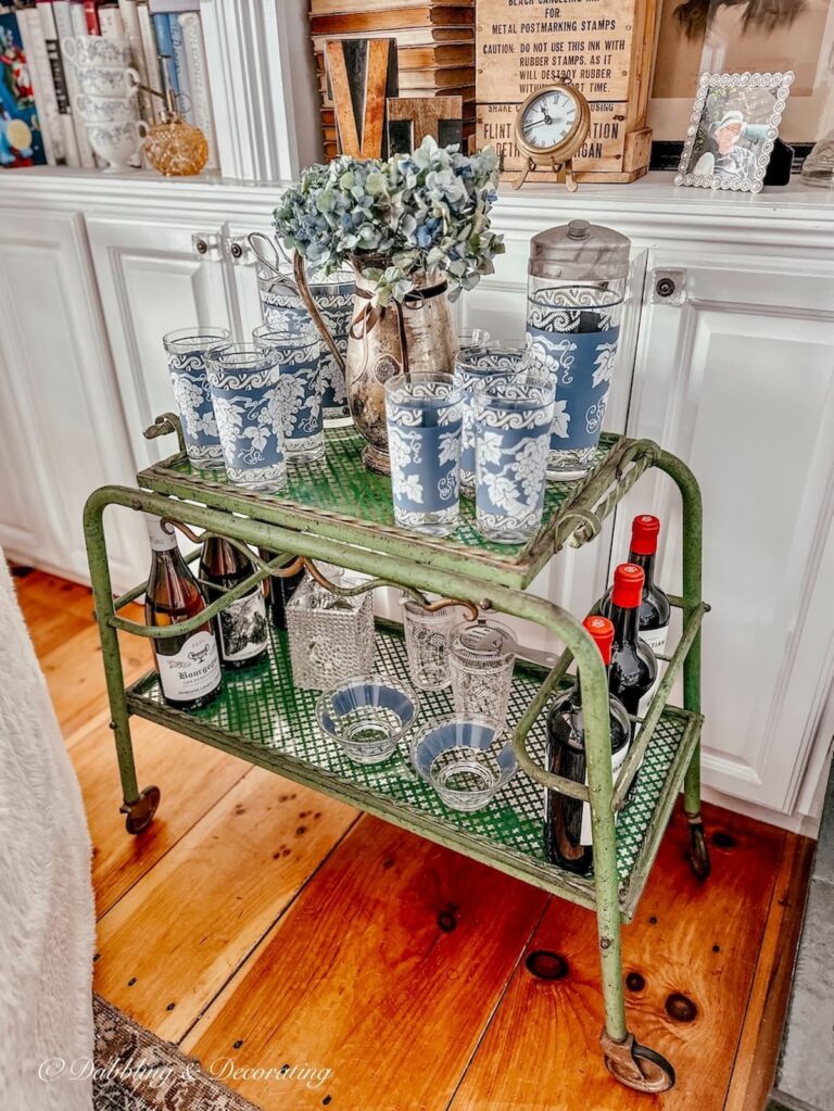 Vintage blue Jeanette barware on antique bar cart as side table in living room.