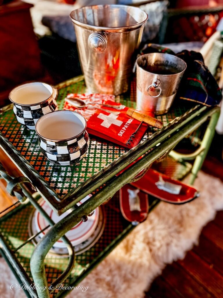 Antique bar cart with mugs, napkins silver ice bucket on outdoor winter porch on sheepskin.