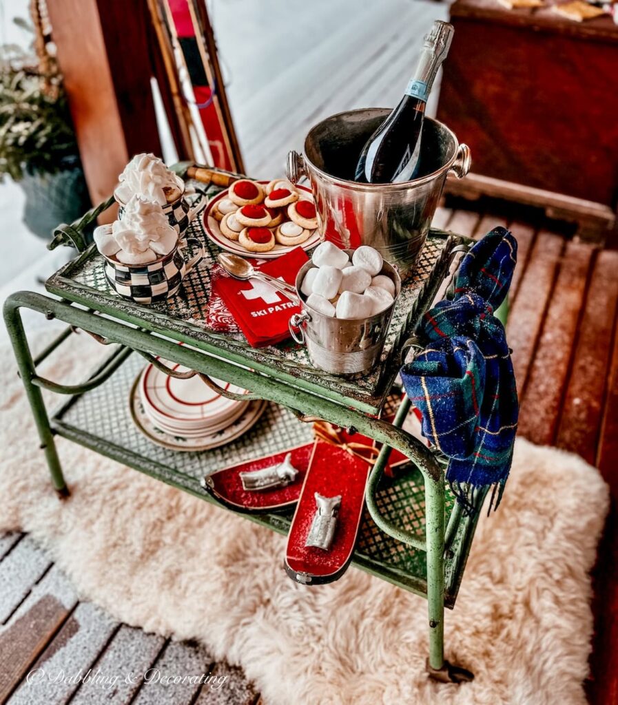 Antique bar cart set up for apres' ski on wintery snowy porch on sheepskin rug.