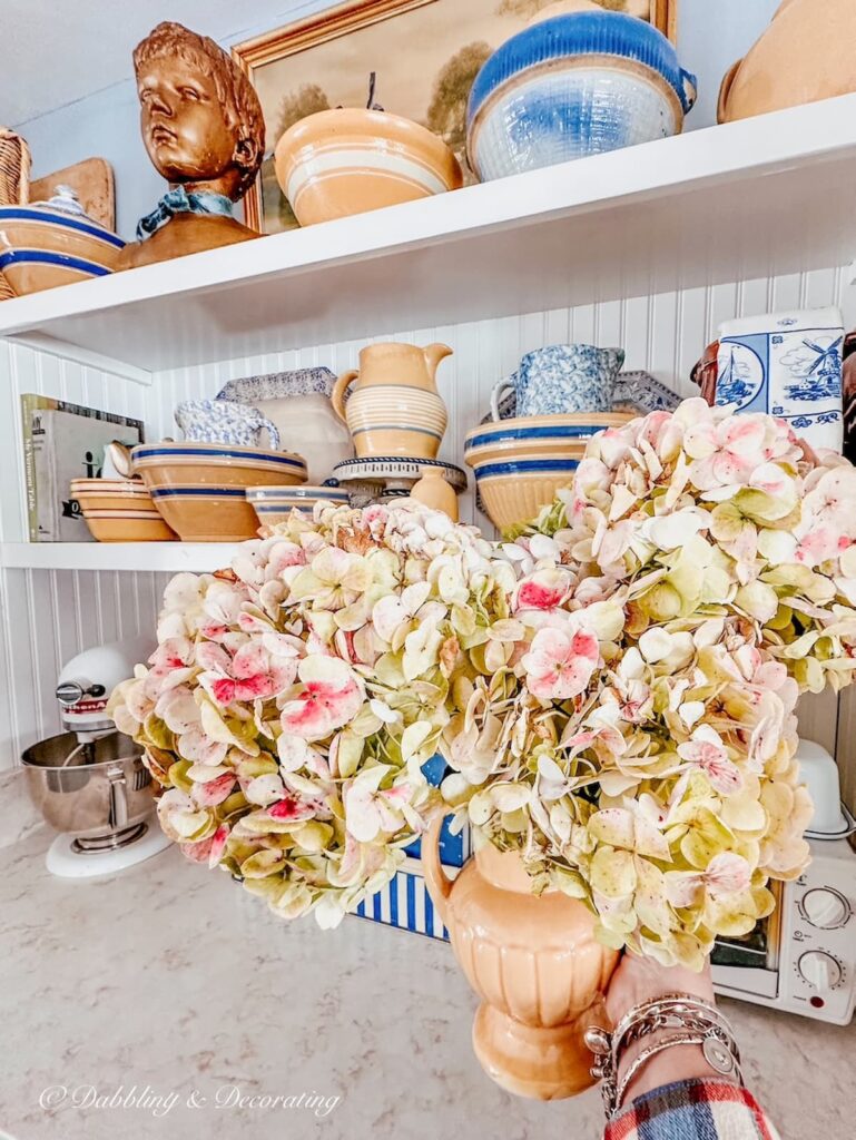 Vintage Yellow McCoy vase with pink hydrangeas in hand in kitchen.