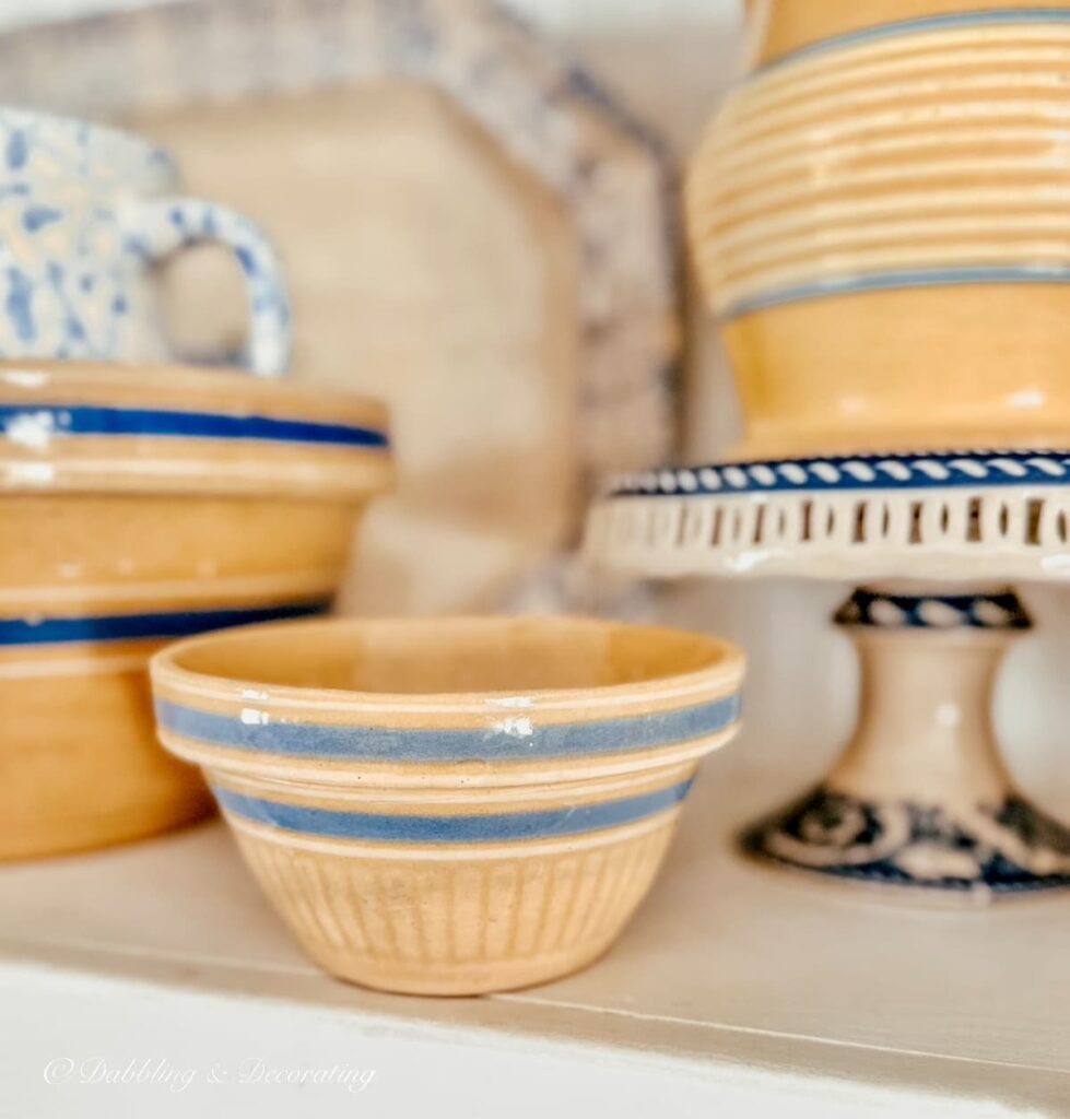 Yellow ware small bowls with blue stripes on kitchen shelving.