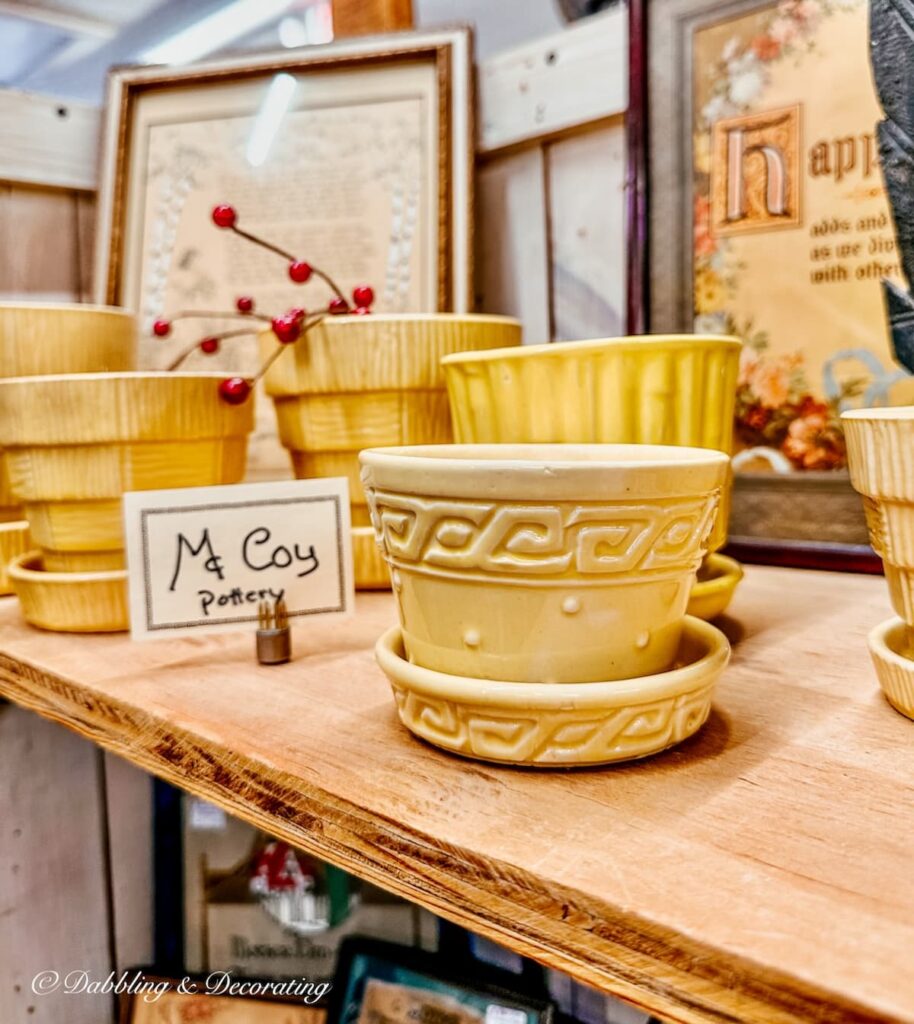 Antique yellowware McCoy vases on antique store shelf.