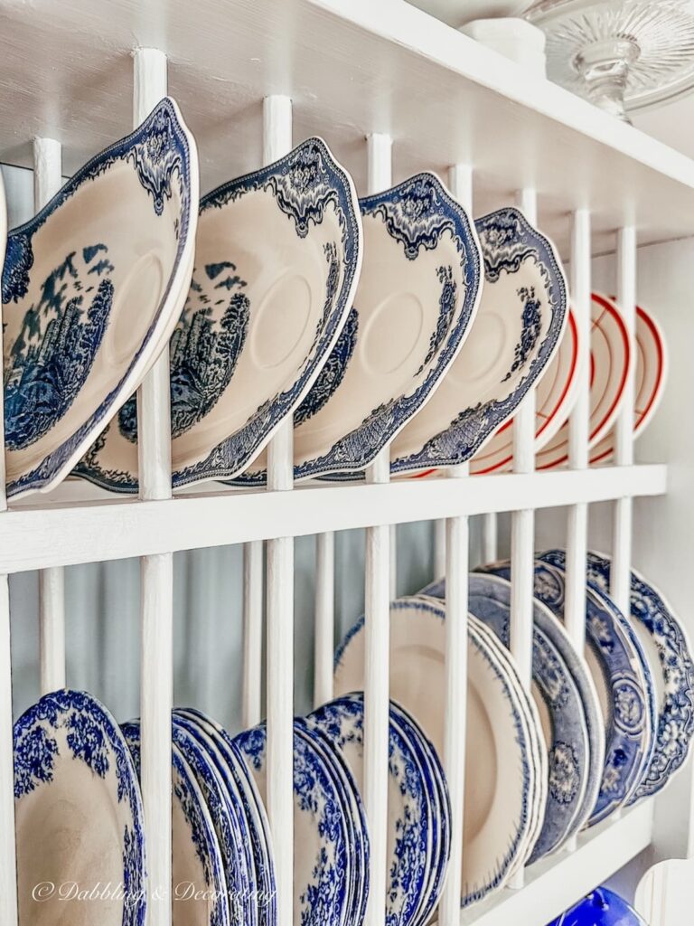 Vintage blue and white plates displayed in white dish rack close up.