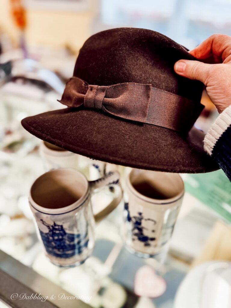 Brown woman's hat in hand at thrift store.