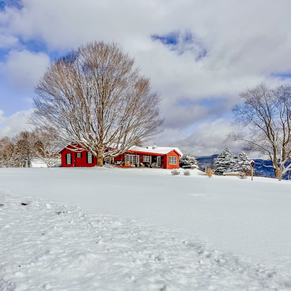 Red Ranch house in the snow in the mountains.