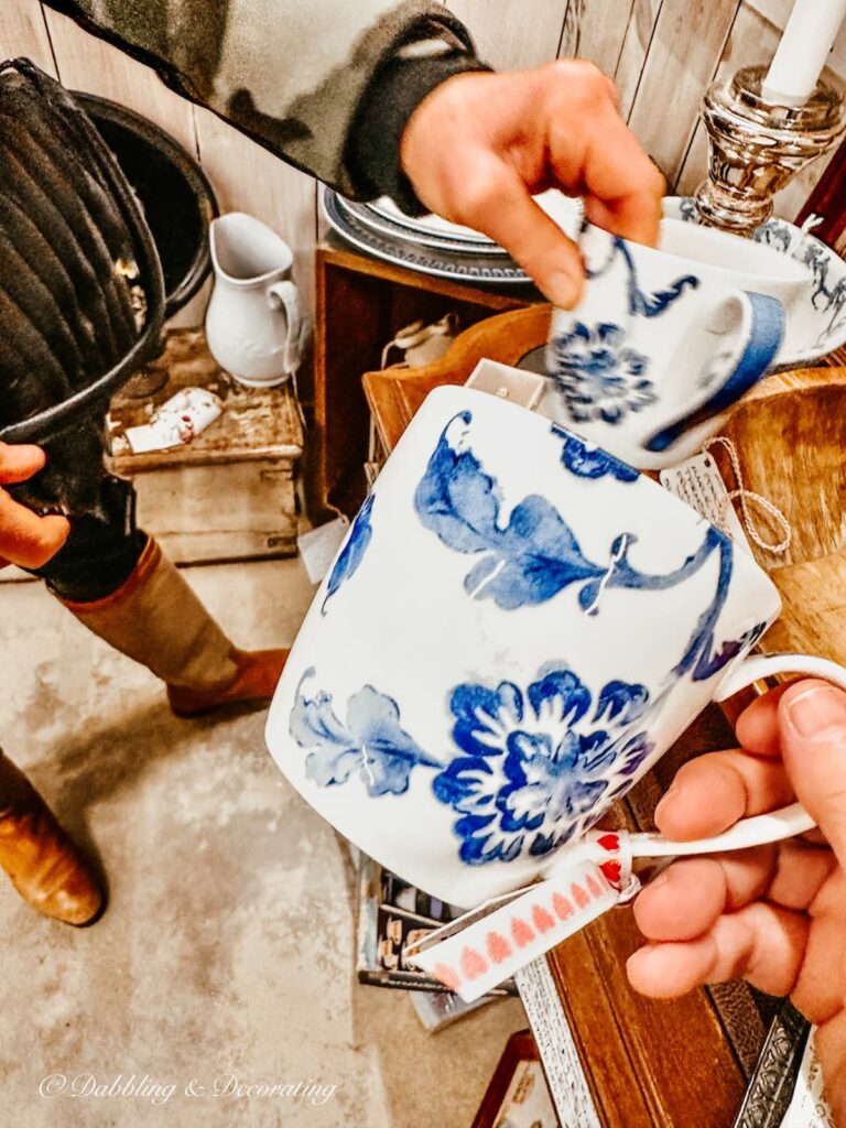 blue and white mugs in hands at antique store for eclectic interiors.