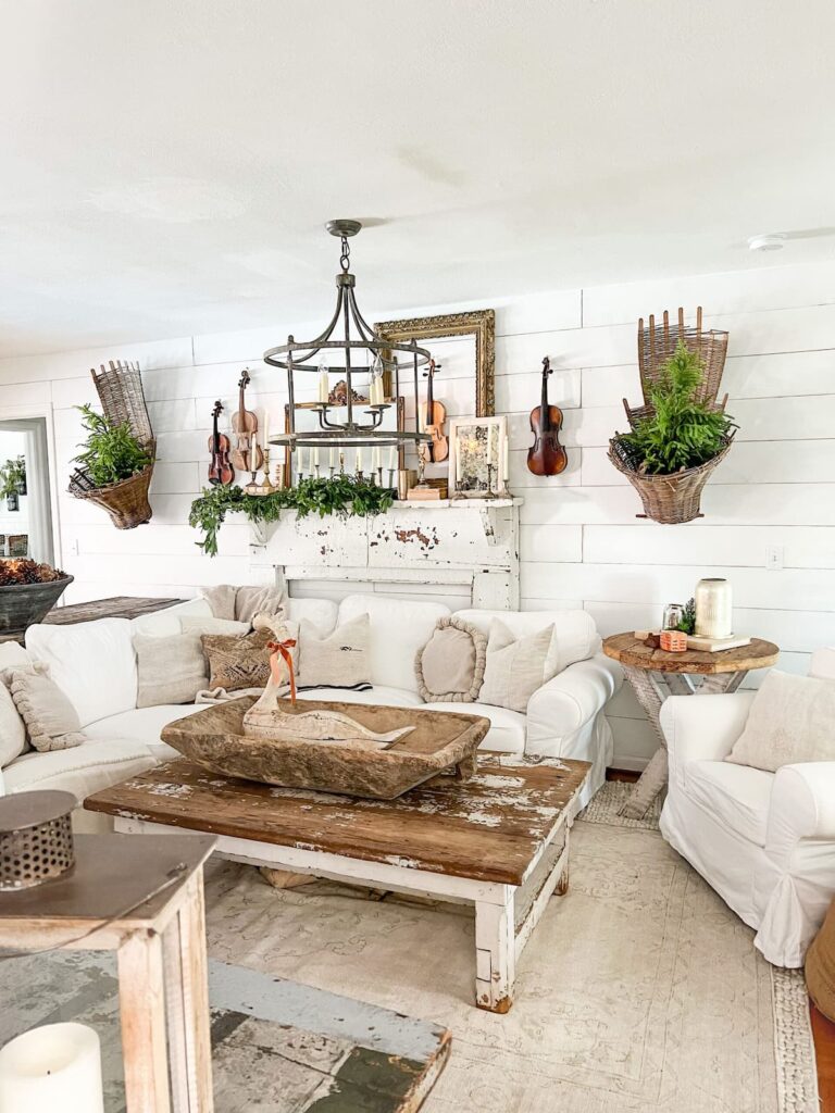 White farmhouse living room design with layered mirrors on mantel.