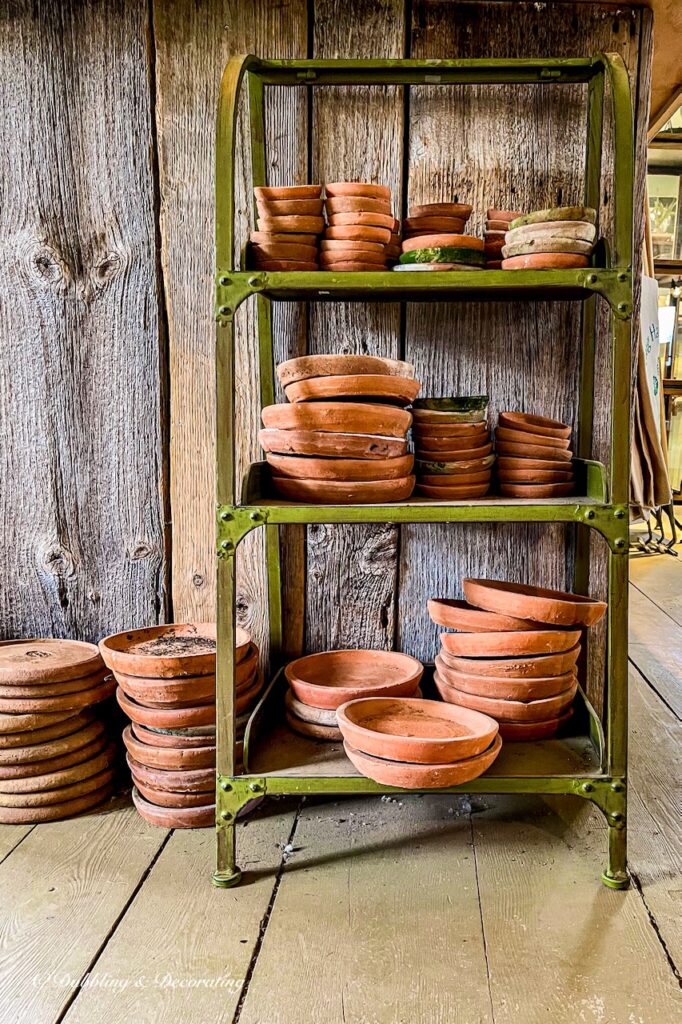 Green Metal shelving with stacks of terracotta pots.