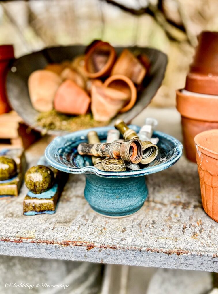 Blue clay pot with vintage nose nozzles and stacks of terracotta pots.